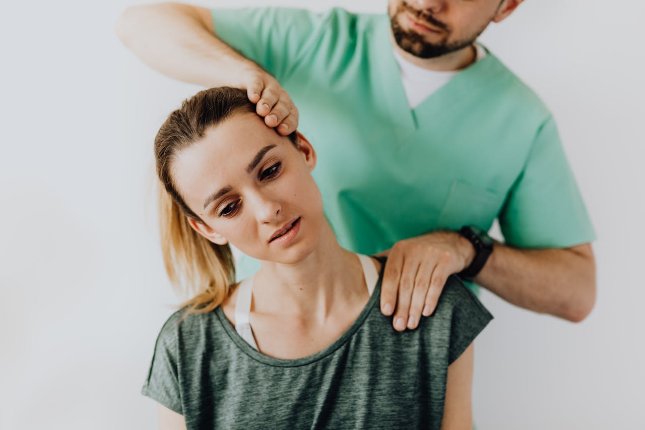 Positive male massage therapist gently massaging female patients neck and shoulders while stretching neck muscles