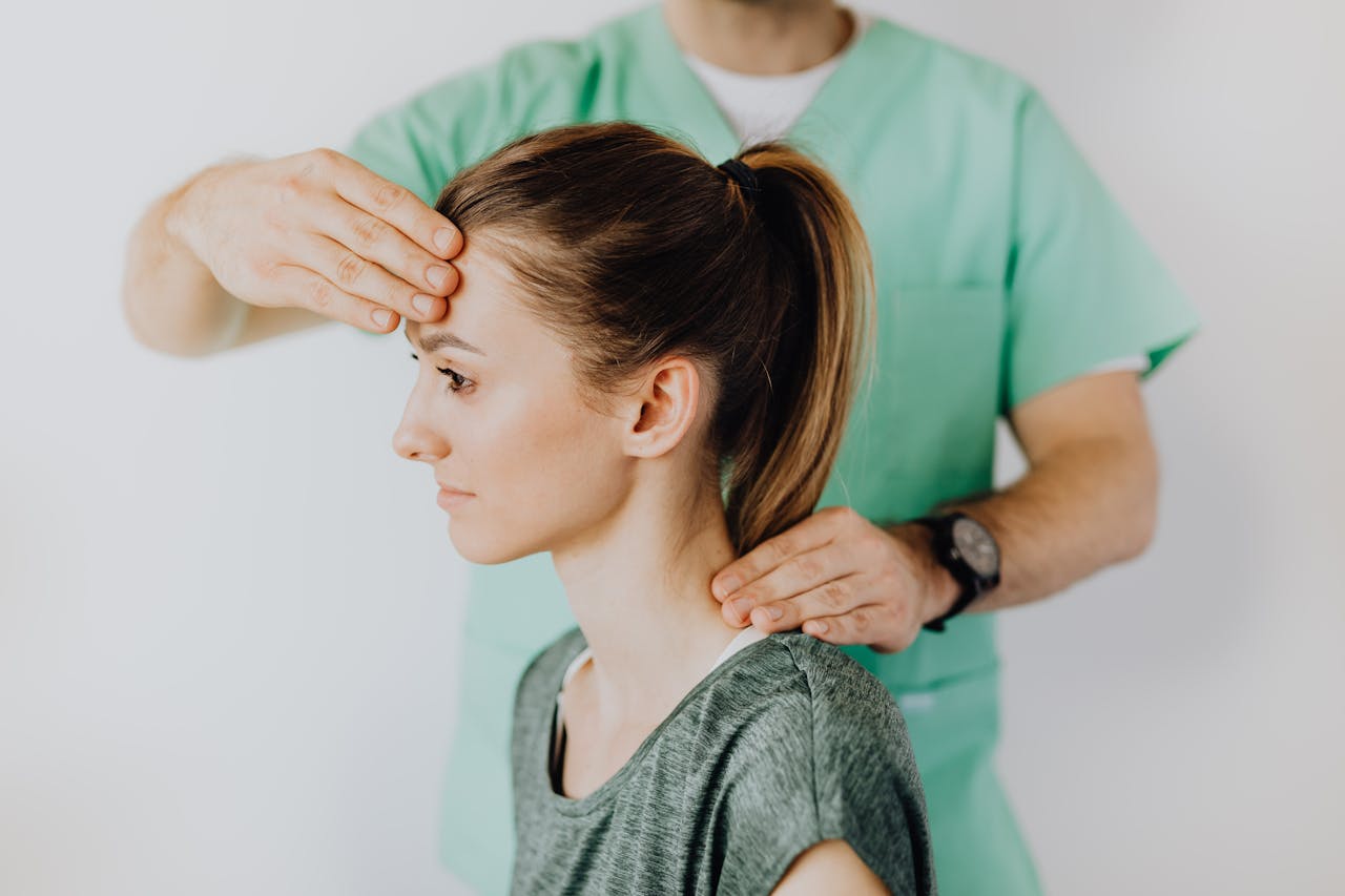 Professional massage therapist performing head and neck massage on content female patient relieving sore neck tensions